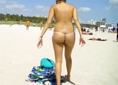 Девушка загорает в стрингах без лифчика на обычном пляже