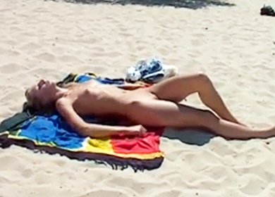 Длинноногая блондинка с маленькой грудью загорает на пляже
